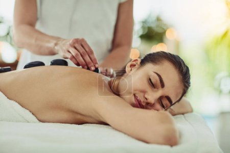 Photo for Health, relax and woman getting a hot stone back massage at spa for luxury, calm and natural self care. Beauty, body care and tranquil female person sleeping while doing rock body treatment at salon - Royalty Free Image