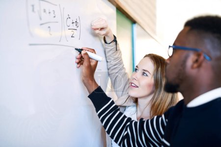 Photo for Sharing an important technique. a young man writing on a whiteboard while students look on - Royalty Free Image