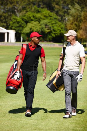 Téléchargez les photos : Prêt pour le prochain round. deux hommes portant leurs sacs de golf sur un terrain de golf - en image libre de droit