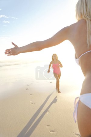 Téléchargez les photos : Courir dans les bras des mamans. une jeune fille courant vers sa mère à la plage - en image libre de droit