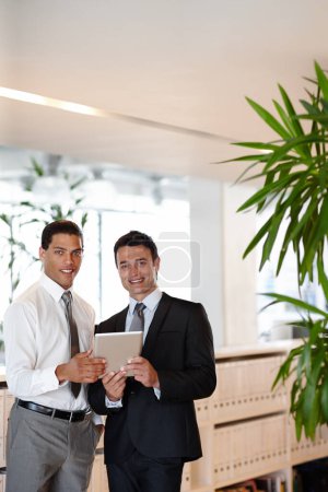 Foto de Usar la tecnología para mejorar su negocio. Dos hombres de negocios vestidos de traje trabajando juntos mientras están en la oficina - Imagen libre de derechos