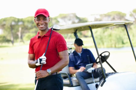 Foto de Tener un gran día en el green. Retrato de un joven en un campo de golf con su amigo esperando en el carro en el fondo - Imagen libre de derechos