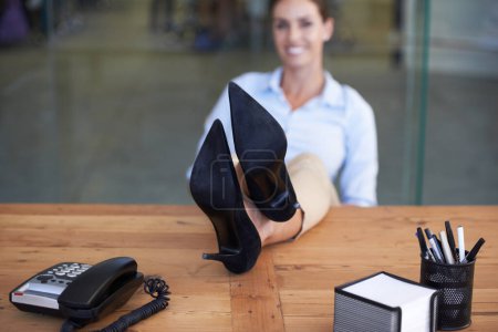 Foto de Por un trabajo bien hecho. Una mujer de negocios sentada con los pies en su escritorio - Imagen libre de derechos