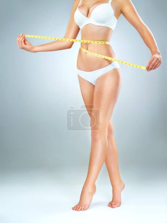 Photo for Woman in underwear, body and measuring tape, lose weight and fitness with abdomen isolated on studio background. Female person, waist measurement and diet with health, weightloss and exercise. - Royalty Free Image