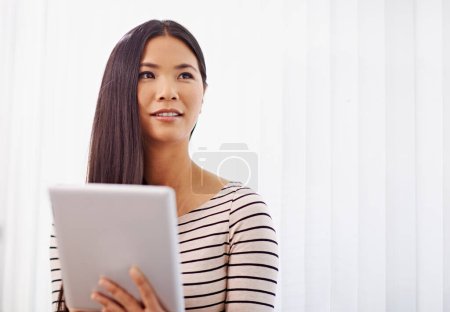 Foto de Pensando en sus objetivos profesionales. Una joven mujer de negocios asiática usando una tableta digital en la oficina - Imagen libre de derechos