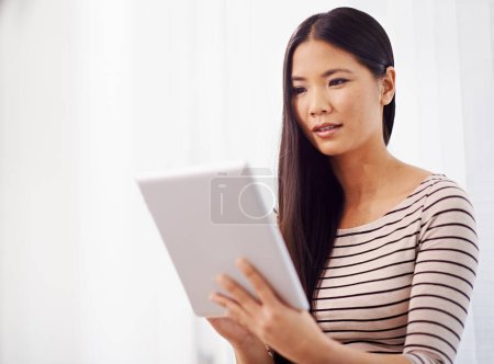 Photo for It seems my day is full of meetings today. a young asian businesswoman using a digital tablet in the office - Royalty Free Image