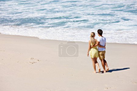 Foto de Nada como un romance de verano. Vista trasera de una feliz pareja joven disfrutando de un romántico paseo por la playa - Imagen libre de derechos