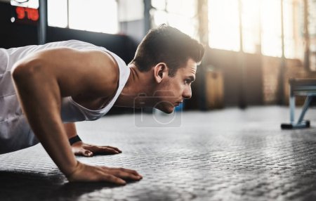Téléchargez les photos : Fitness appartient à la focalisée. un jeune homme faisant des pompes dans une salle de gym - en image libre de droit