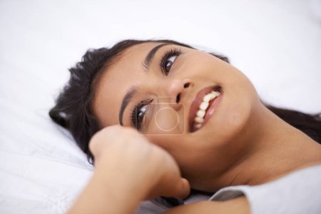Photo for Phoning a friend. A young woman lying on her back while talking on the phone - Royalty Free Image