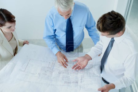 Photo for Finalizing the new head office plans. a three businesspeople going over blueprints - Royalty Free Image