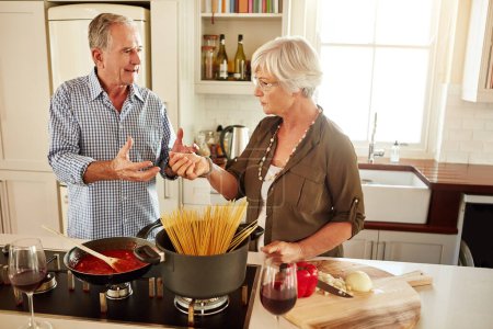 Photo for Talking, food or old couple in kitchen cooking with healthy vegetables for lunch meal or dinner together. Spaghetti or woman helping or speaking to mature husband in meal preparation in retirement. - Royalty Free Image