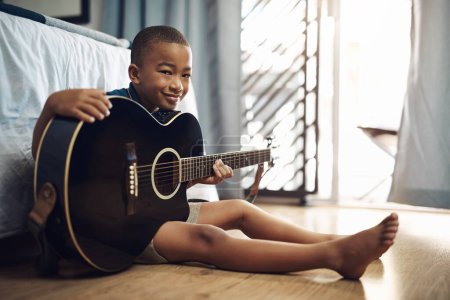 Foto de Mira lo que tengo para Navidad. un joven tocando la guitarra en casa - Imagen libre de derechos