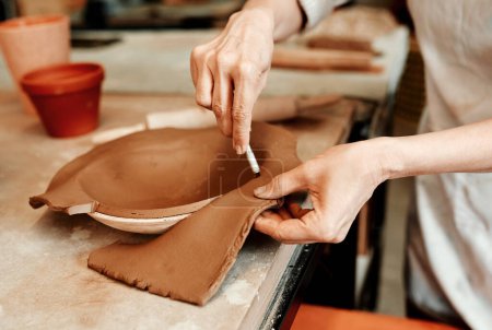 Téléchargez les photos : Laissons tomber l'excès d'argile. un artisan méconnaissable travaillant dans un atelier de poterie - en image libre de droit
