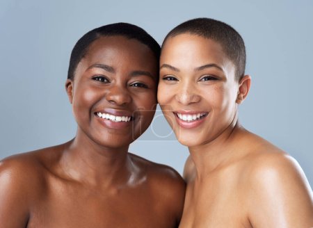 Photo for Shes my other half. Portrait of two beautiful young women standing close to each other against a grey background - Royalty Free Image