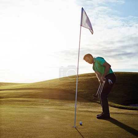 Téléchargez les photos : Un coup et c'est dedans. un jeune homme passe la journée sur un terrain de golf - en image libre de droit