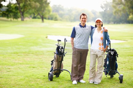 Foto de Feliz pareja de golf. Longitud completa de la feliz pareja de golf con los brazos alrededor y sonriendo - Imagen libre de derechos