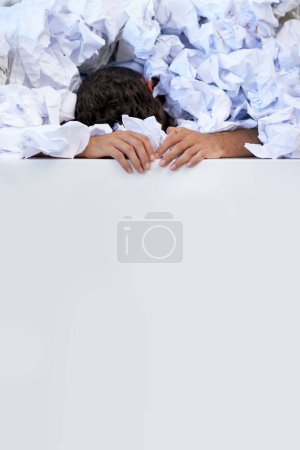 Photo for Works got him pinned down. a businessman buried under a pile of crumpled up paperwork - Royalty Free Image