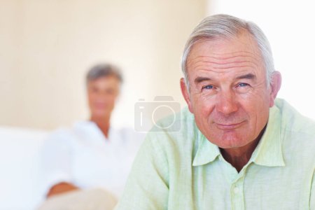 Photo for Smiling mature man with woman in background. Portrait of handsome mature man smiling with woman in background - Royalty Free Image