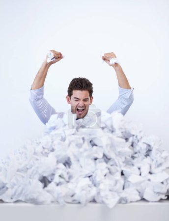 Photo for The paperwork keeps piling up around him. A young businessman buried in paperwork showing his frustration - Royalty Free Image