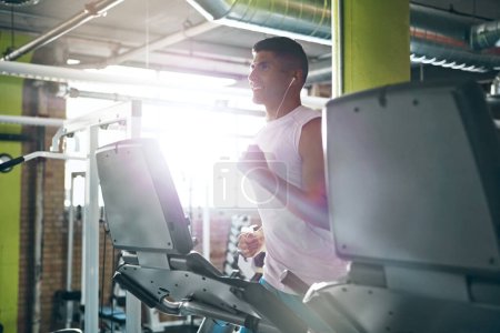 Téléchargez les photos : Maximiser son entraînement sur tapis roulant. un jeune homme travaillant seul dans la salle de gym - en image libre de droit