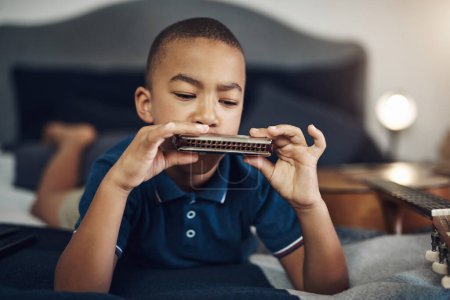 Foto de Hagamos algo de música. un joven tocando la armónica en casa - Imagen libre de derechos