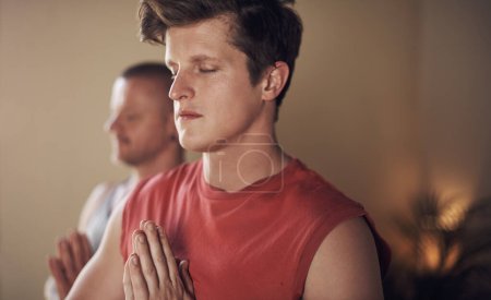 Téléchargez les photos : S'inquiéter vole seulement aujourd'hui la paix. deux jeunes yogis debout ensemble et méditant avec leurs paumes ensemble après une séance de yoga intérieur - en image libre de droit