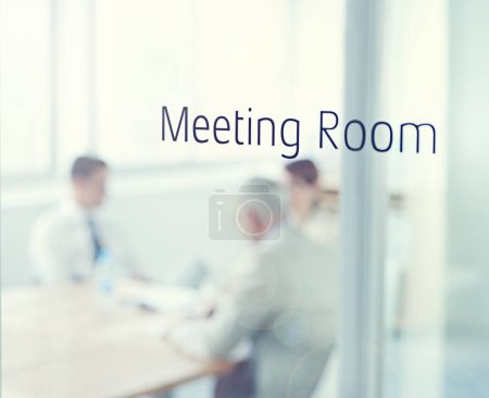 Foto de La reunión está en sesión. Primer plano de una puerta de cristal que lee la sala de reuniones con gente de negocios borrosa en la habitación detrás - Imagen libre de derechos