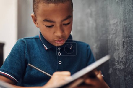 Foto de La escritura es un vehículo de comunicación, conexión y creatividad. un joven escribiendo en un libro mientras está sentado en casa - Imagen libre de derechos