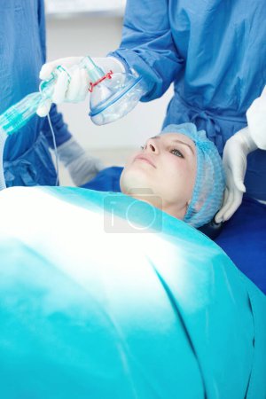 Photo for Count down from ten. Medical staff administering anaesthesia to a female patient in a hospital - Royalty Free Image