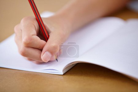 Photo for Working hard at school. A cropped closeup image of a child writing in his workbook at school - Royalty Free Image