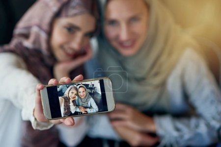 Téléchargez les photos : Femmes musulmanes, amies et selfie avec téléphone portable, sourire et bonheur pour publication sur blog, web ou réseaux sociaux. Heureuse femme islamique, groupe et smartphone pour la photographie, photo de profil ou mémoire sur l'application. - en image libre de droit