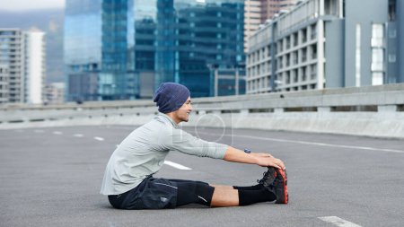 Téléchargez les photos : Je suis prêt pour la course. un jeune joggeur masculin s'étirant dans une rue vide avant une course - en image libre de droit