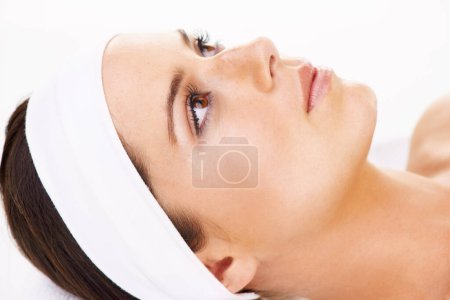 Foto de Tratándose de un tratamiento de belleza. una mujer joven acostada en una cama de masaje aislada en blanco - Imagen libre de derechos