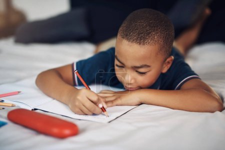 Foto de Estoy escribiendo sobre mi día. un niño usando un lápiz mientras escribe en casa - Imagen libre de derechos