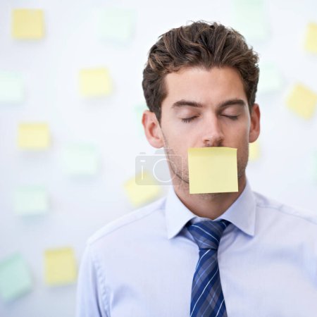 I had to sign a confidentiality agreement. a young office worker with a sticky note stuck over his mouth