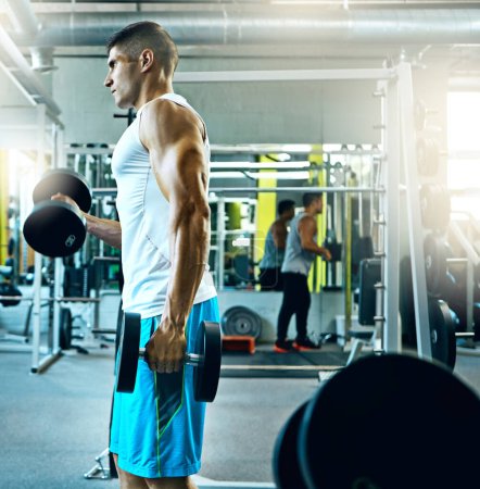 Téléchargez les photos : Choisir d'être en grande forme. un jeune homme travaillant seul dans la salle de gym - en image libre de droit