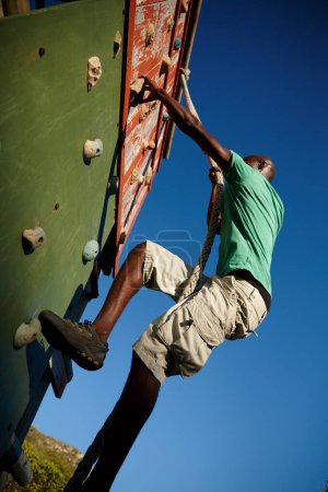 Photo for Energy and persistence conquer all things. a young man climbing over an obstacle at military bootcamp - Royalty Free Image