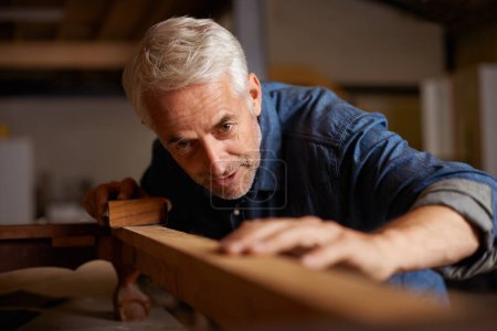 Téléchargez les photos : Il sait s'y prendre avec le bois. un charpentier masculin mature travaillant sur un projet dans son atelier - en image libre de droit
