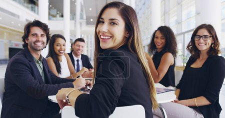 Téléchargez les photos : Nous faisons de notre mieux dans la salle de réunion. une jeune femme d'affaires souriante dans un bureau lors d'une rencontre avec ses collègues en arrière-plan - en image libre de droit
