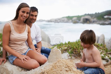 Photo for Family, child and sand castle portrait at beach in summer for fun, travel or holiday. A man, woman and kid playing together on vacation at sea for quality time, development and happiness outdoor. - Royalty Free Image