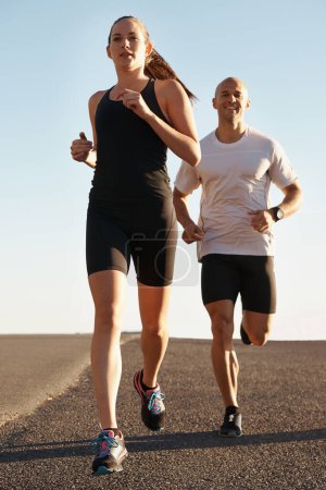 Téléchargez les photos : Route, entraînement et entraîneur personnel courir avec la femme comme entraînement ou exercice matinal pour la santé et le bien-être. Sport, homme et coureur de rue avec athlète comme condition physique pour un marathon, le sport et l'énergie. - en image libre de droit