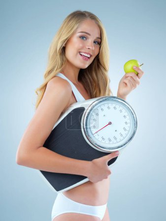 Photo for Happy woman in portrait, apple and scale, lose weight and healthy food isolated on studio background. Female model with smile, health and diet with organic fruit with happiness and weightloss. - Royalty Free Image