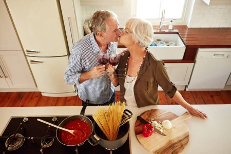 Photo for Kiss, wine toast or old couple cooking food for a healthy vegan diet together with love in retirement at home. Top view of senior woman drinking or kissing in kitchen with mature husband at dinner. - Royalty Free Image