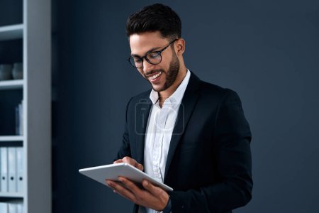 Photo for Business on the go is easier nowadays. a handsome young businessman standing alone and using a tablet against a gray background in the studio - Royalty Free Image