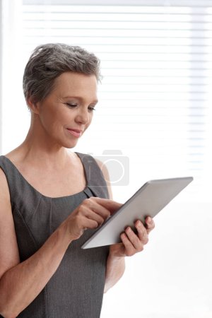 Photo for Using targeted advertising to draw in customers. A mature businesswoman working on her digital tablet at the office - Royalty Free Image