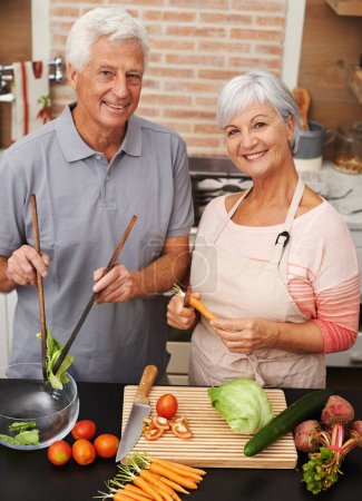 Foto de Cocina, salud y sonrisa con retrato de pareja anciana en cocina para ensalada, amor y nutrición. Feliz, ayuda y jubilación con hombres y mujeres mayores comiendo en casa para la comida, la cena y la receta. - Imagen libre de derechos