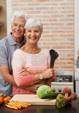 Téléchargez les photos : Cuisine, heureux et portrait de vieux couple dans la cuisine pour la salade, l'amour et la nutrition. Santé, sourire et retraite avec un homme et une femme âgés coupant des légumes à la maison pour la nourriture, le dîner et la recette. - en image libre de droit