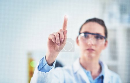 Photo for One bright idea coming up. a focused young female scientist wearing protective glasses while pointing with her finger on a glass wall - Royalty Free Image