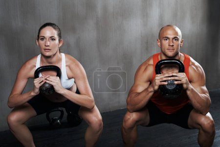 Photo for Fitness, people and portrait with kettlebell in squat for weightlifting or exercise together at gym. Serious man and woman lifting weight for strong exercising, power or glutes in training indoors. - Royalty Free Image