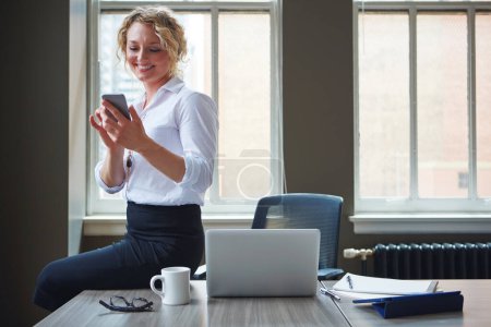 Foto de Actualizaciones instantáneas mediante mensajería instantánea. una mujer de negocios usando un teléfono en una oficina - Imagen libre de derechos